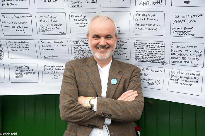 Fig.27 Colm O'Gorman outside the entrance to the Monastery of the Sisters of Charity of Refuge Convent. 
Behind him is one of the sheets upon which participants on the parade wrote messages of support and solidarity.